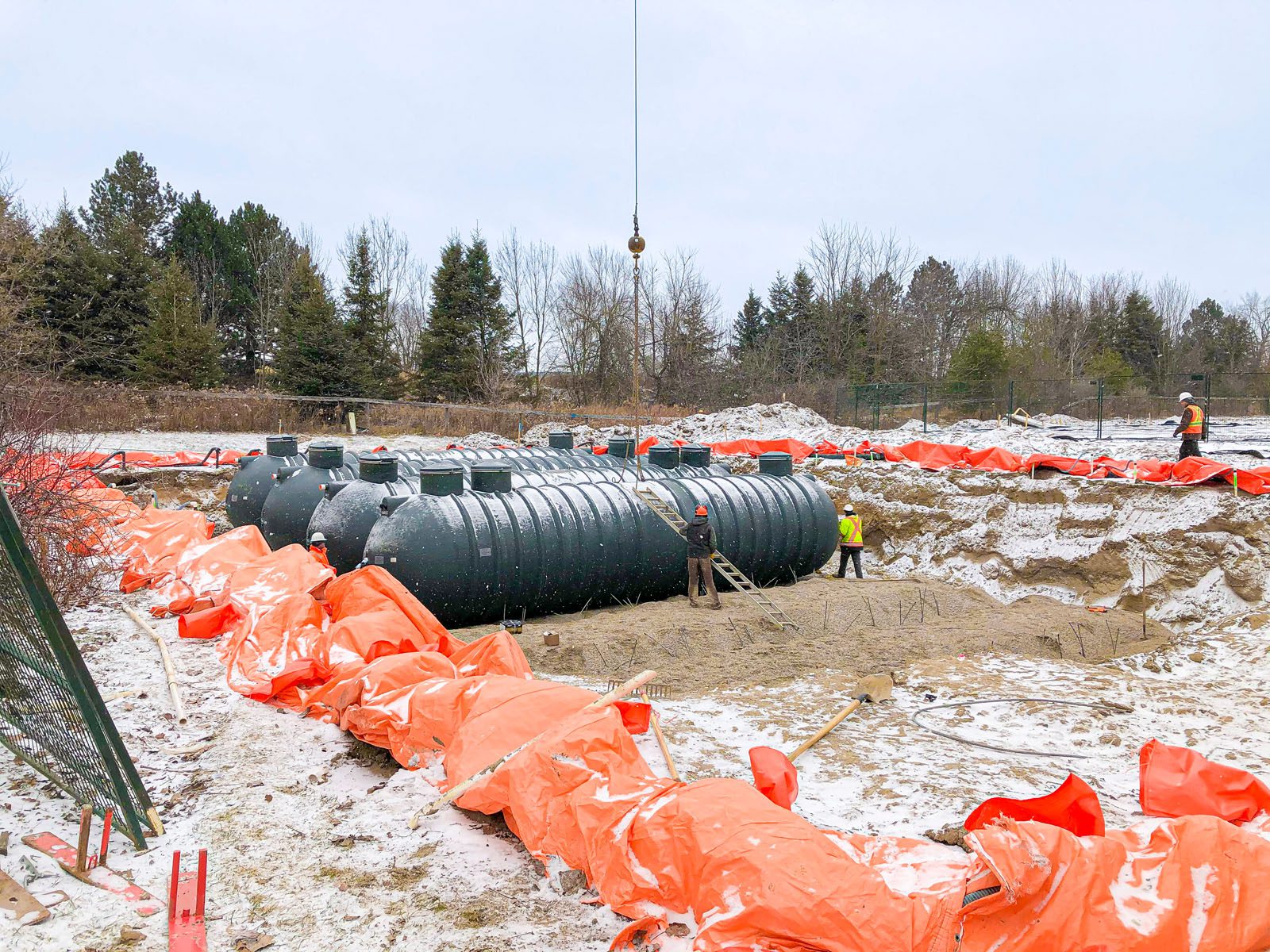 Large Black Storage Tanks being Craned into a Hole